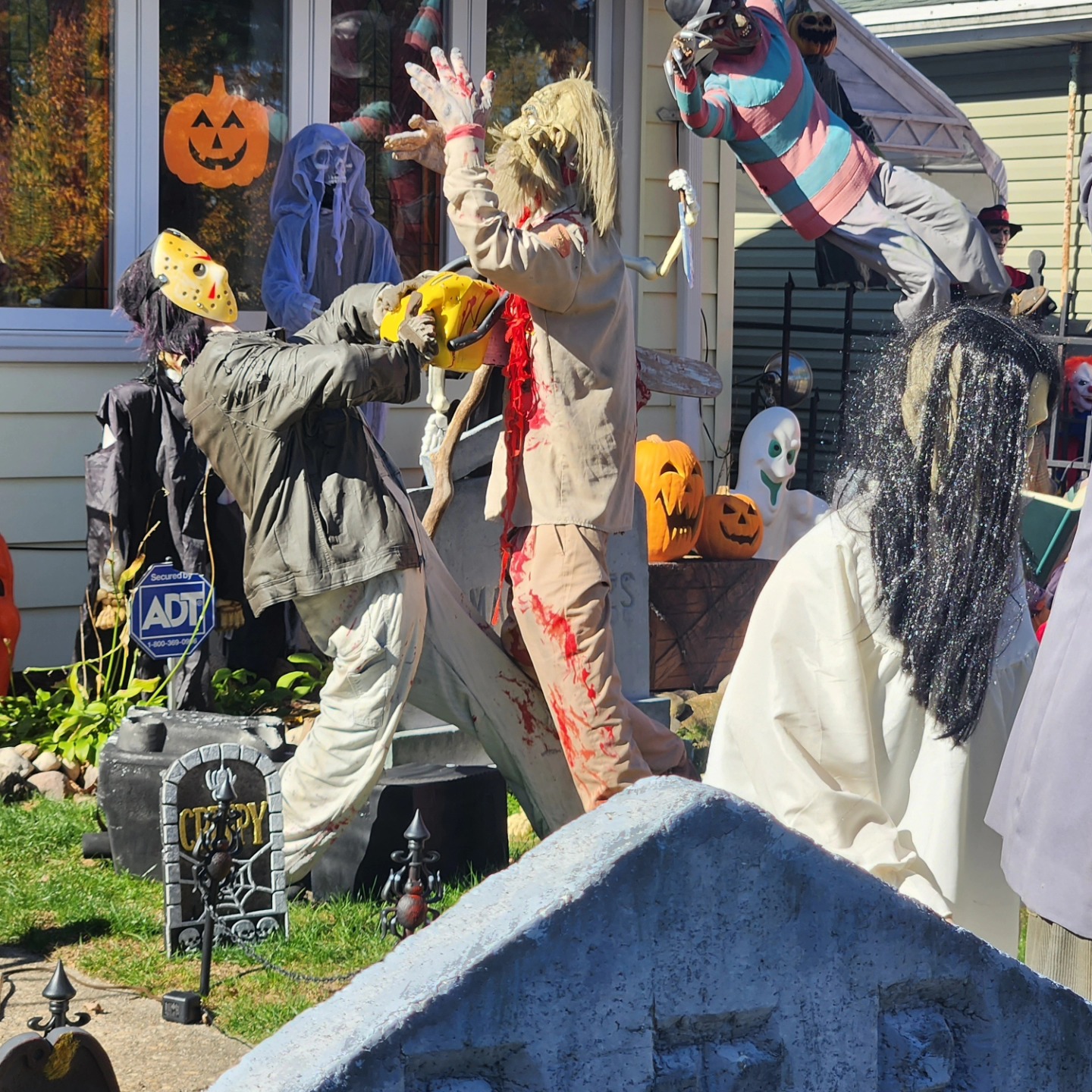An alternate view of the prop chainsaw scene with a red-cloaked figure behind the fence — Hills of Unrest, October 2024.
