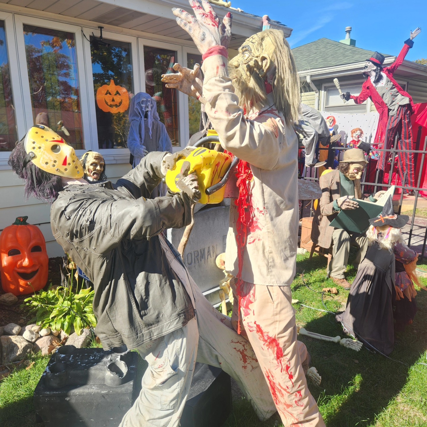 A horror figure holding a prop chainsaw with pumpkins and other figures behind it — Hills of Unrest, October 2024.